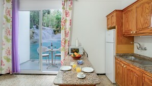 Una cocina con armarios de madera, encimera de granito y vistas a una cascada a través de una puerta corrediza de vidrio.
