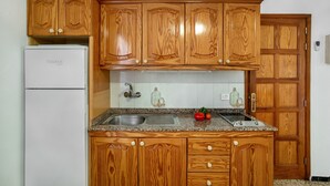 Una cocina con armarios de madera, un lavamanos de acero inoxidable y un refrigerador blanco.