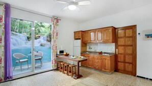 Una cocina con armarios de madera, una mesa de comedor y vistas a una cascada a través de puertas de cristal.