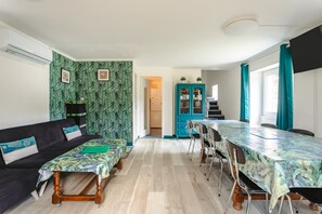 A room with a sofa, a dining table, a cabinet, and a staircase. - Holiday Home 'Du Parc' with Lake View, Wi-Fi and Air Conditioning (Genouillé)