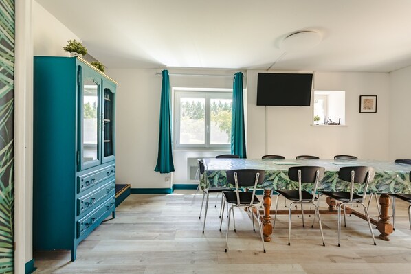 A dining area with a table, chairs, a cabinet, and a TV on the wall.