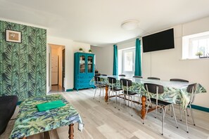 A dining area with a table, chairs, a cabinet, and a TV mounted on the wall. - Holiday Home 'Du Parc' with Lake View, Wi-Fi and Air Conditioning (Genouillé)