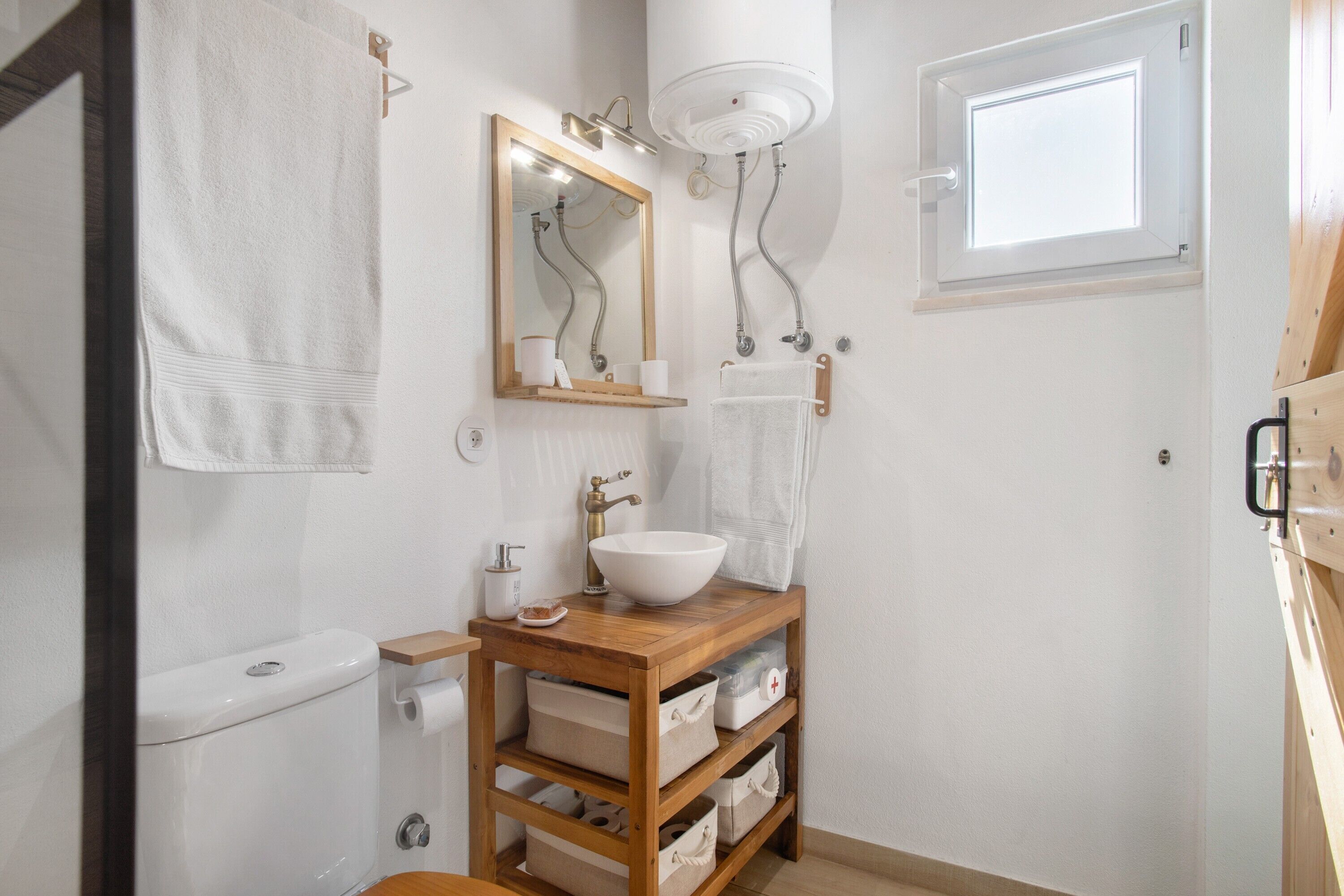 Une salle de bain comprenant des toilettes, un lavabo, un miroir, un porte-serviettes et une fenêtre.