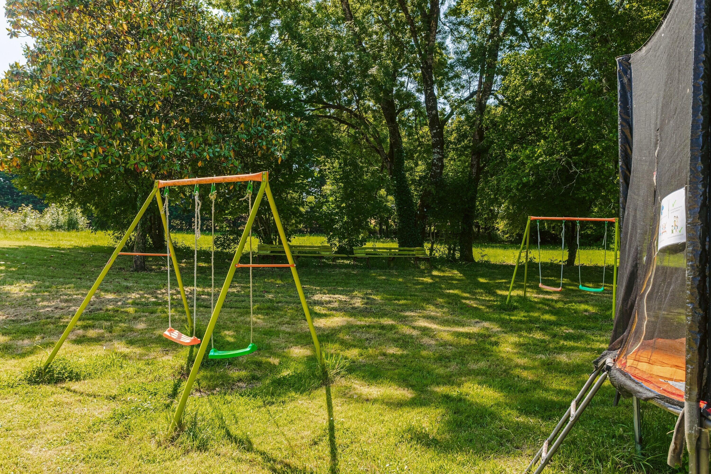 A grassy area with swings and a tent.