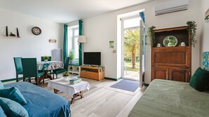 Une pièce comprenant un lit, un bureau avec une chaise, une télévision et un meuble orné d’une plante.
