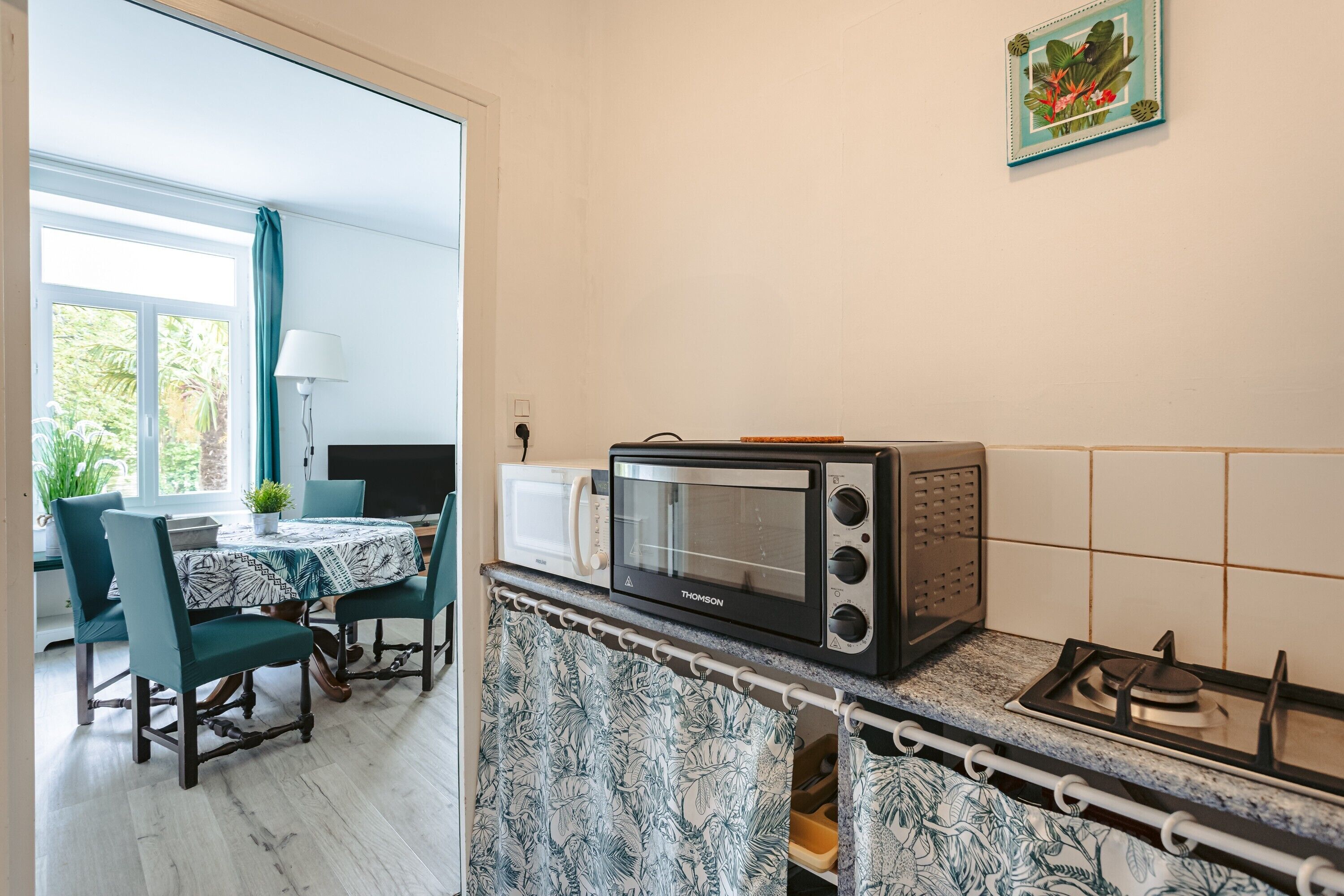 Een keuken met een magnetron, een gasfornuis, een tafel met stoelen en uitzicht op de omgeving.