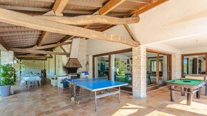 Un espace extérieur abrité comprenant une table de ping-pong, une table de billard et un mur en pierre.