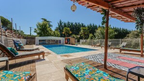 Un espace extérieur avec une piscine, des chaises longues, une pergola et une zone délimitée par une clôture.