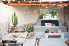 A cozy outdoor seating area with a stone wall, a cactus, and a table set for dining.