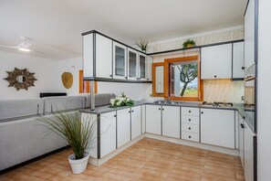 A modern kitchen with white cabinets, a built-in stove, and a window with a view.