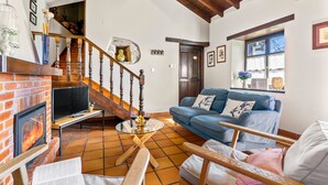 A living room with a fireplace, a sofa, a coffee table, and a staircase. - Rural House 'El Llagar De Naveda' with Mountain Views, Private Terrace & Wi-Fi (Naveda)
