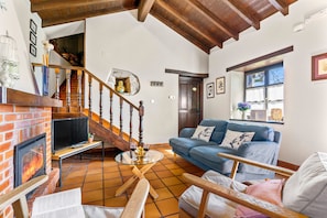 Ein Wohnzimmer mit Kamin, einer Couch, einem Couchtisch und einer Treppe.