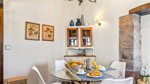 A breakfast table with chairs, a fruit basket, a coffee pot, and a glass of orange juice. - Rural House 'El Llagar De Naveda' with Mountain Views, Private Terrace & Wi-Fi (Naveda)