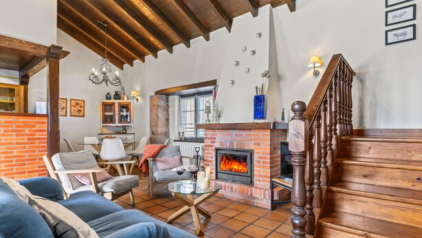 A living room with a fireplace, wooden staircase, and a dining area. - Rural House 'El Llagar De Naveda' with Mountain Views, Private Terrace & Wi-Fi (Naveda)