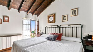 A bedroom with two beds, a wooden ceiling, a window with curtains, and framed pictures on the wall. - Rural House 'El Llagar De Naveda' with Mountain Views, Private Terrace & Wi-Fi (Naveda)