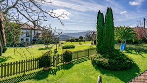 A well-maintained garden with a wooden fence, a bench, and a slide. - Rural House 'El Llagar De Naveda' with Mountain Views, Private Terrace & Wi-Fi (Naveda)