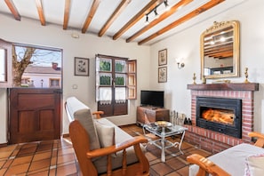 A living room with a fireplace, wooden furniture, a television, and a large window.