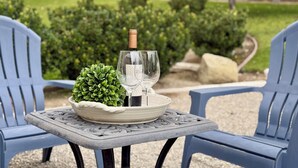 A table with a bottle of wine and two glasses, a potted plant, and a bowl on a table in an outdoor setting with chairs. - Idyllic Vineyard Loft Apartment (Solvang)