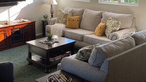 A living room with a sofa, coffee table, TV, and windows. - Idyllic Vineyard Loft Apartment (Solvang)
