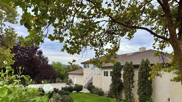 A residential house with a well-maintained lawn, a staircase leading to the entrance, and several mature trees. - Idyllic Vineyard Loft Apartment (Solvang)
