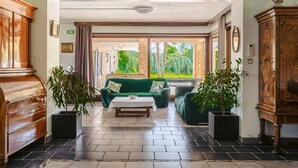 A spacious lobby with a green sofa set, a coffee table, and potted plants.