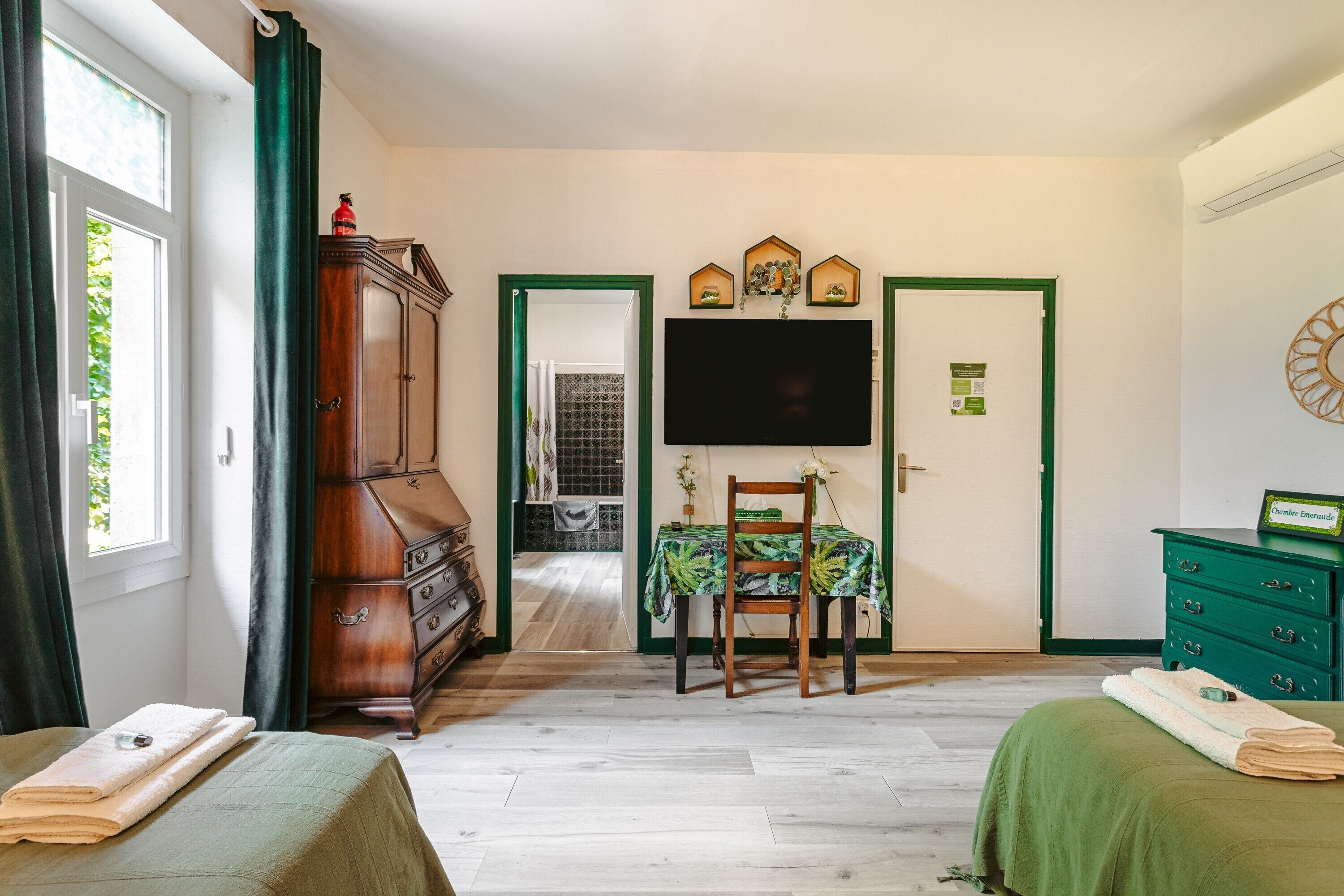 A room with a bed, a dresser, a television, and a dining table with chairs.