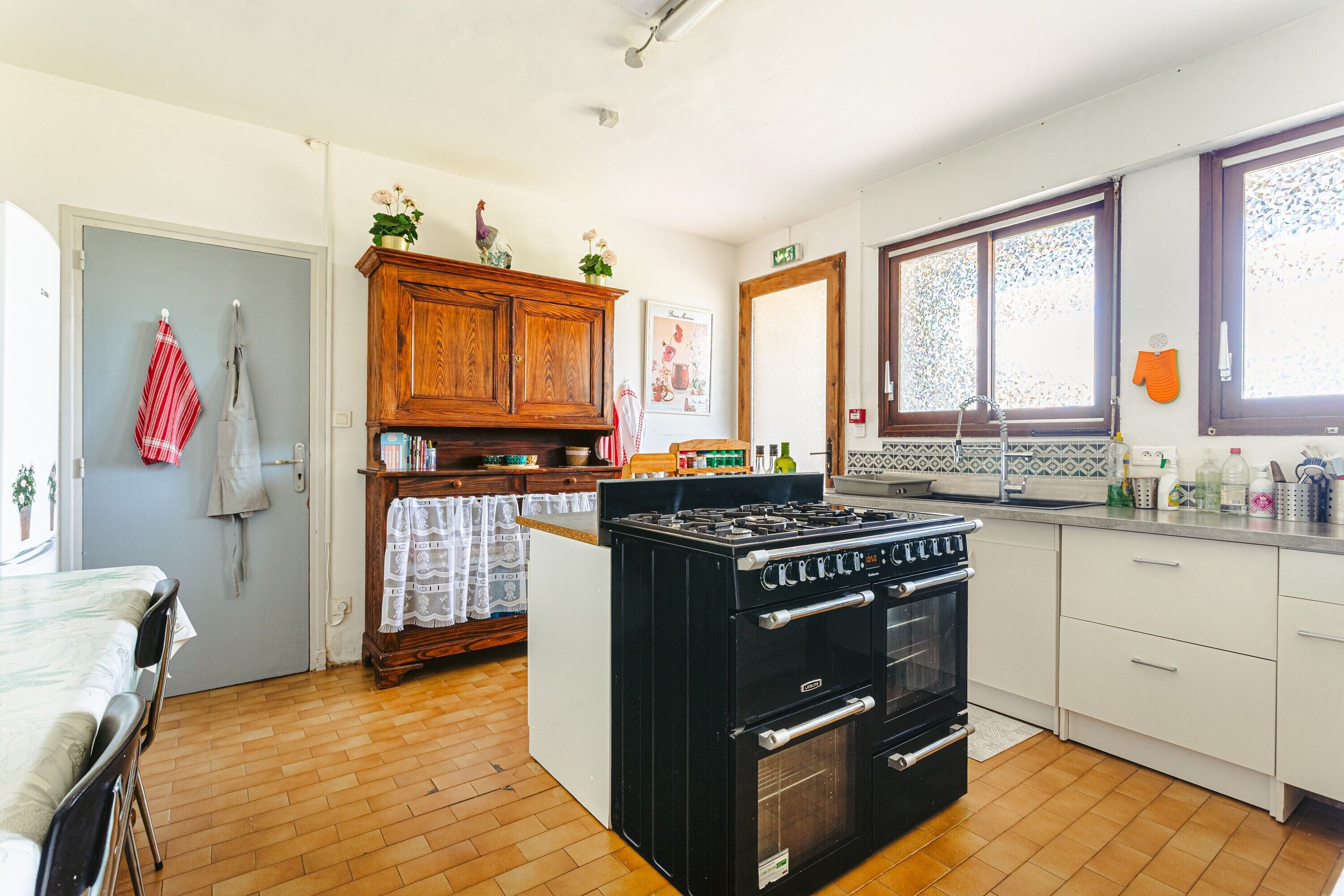 Una cocina con estufa, horno, armarios de madera y una ventana.