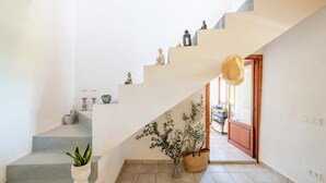 A staircase with a hat on the railing, a plant on the left, and a door at the bottom. - Finca 'Cas Forner' with Mountain Views, Private Pool and Wi-Fi (Illes Balears)