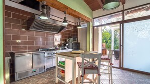 A kitchen with a brick wall, stainless steel appliances, and a dining area with a table and chairs. - Villa 'Apollonion' with Private Pool, Wi-Fi and Air Conditioning (Siracusa)
