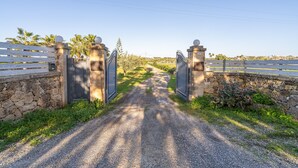 A gravel driveway leading to a gated entrance with stone walls and a white fence. - Villa 'Apollonion' with Private Pool, Wi-Fi and Air Conditioning (Siracusa)
