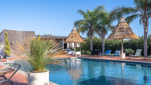 A swimming pool with lounge chairs, palm trees, and thatched umbrellas. - Villa 'Apollonion' with Private Pool, Wi-Fi and Air Conditioning (Siracusa)