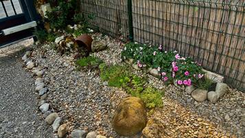 A garden with a gravel path, rocks, and pink flowers.