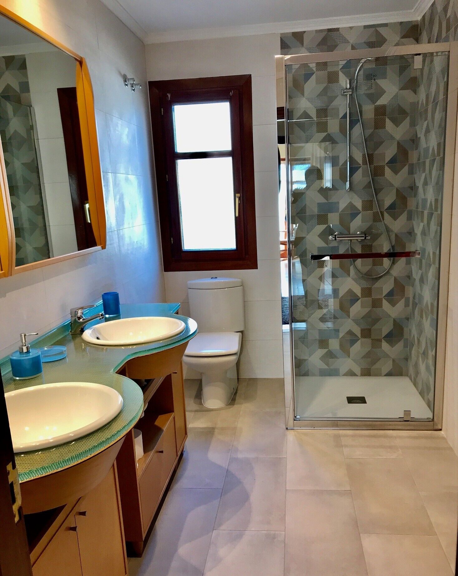 A bathroom with two sinks, a toilet, a shower, and a window.
