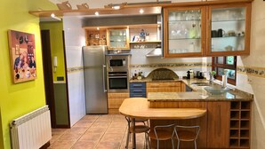 Een keuken met een centraal eiland, houten kastjes, een koelkast en een magnetron.