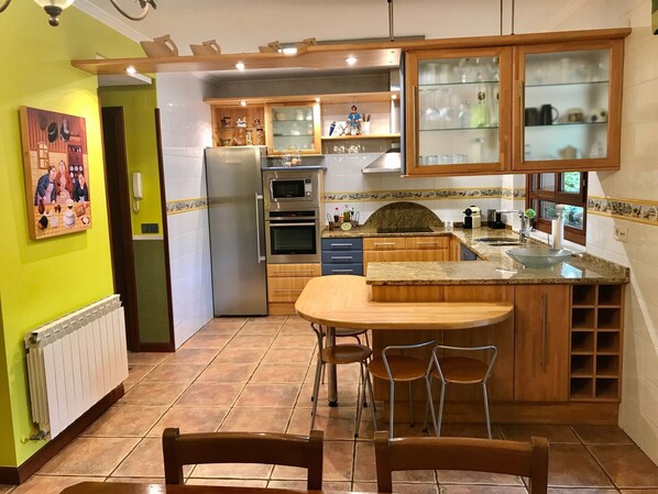 Une cuisine dotée d’un îlot central, de meubles en bois, d’un réfrigérateur et d’un four à micro-ondes.