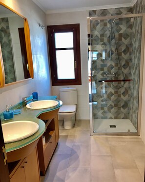 Une salle de bain avec deux lavabos, des toilettes et une douche à parois de verre.