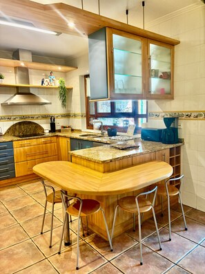 Une cuisine dotée d’un îlot central, de tabourets de bar et d’un four encastré.