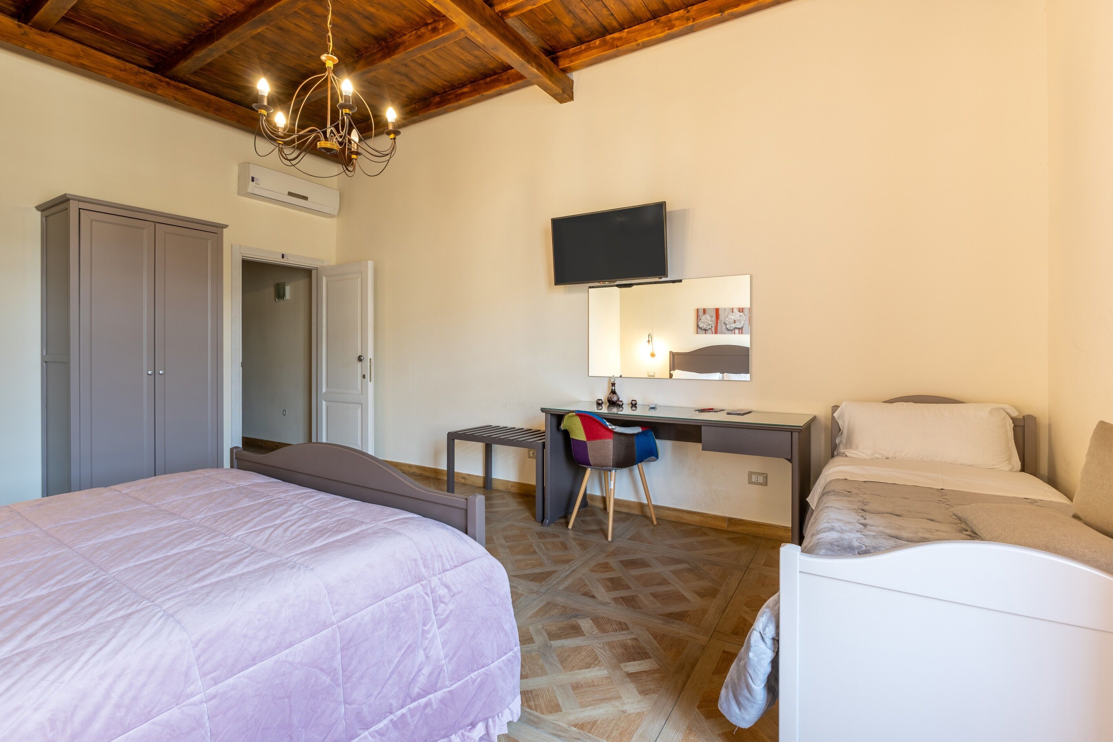 Ein Schlafzimmer mit Bett, Schreibtisch, Stuhl, Fernseher und Kleiderschrank.