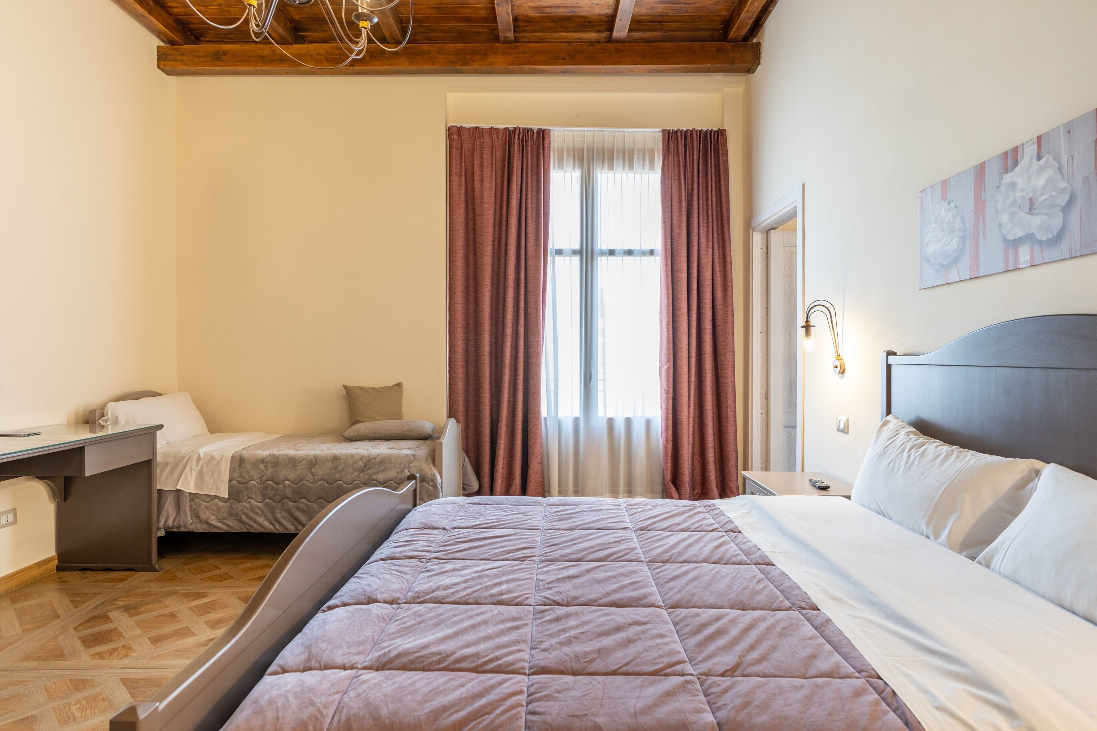 Ein Schlafzimmer mit Bett, Schreibtisch, Stuhl, Nachttisch und einem Fenster mit Vorhängen.