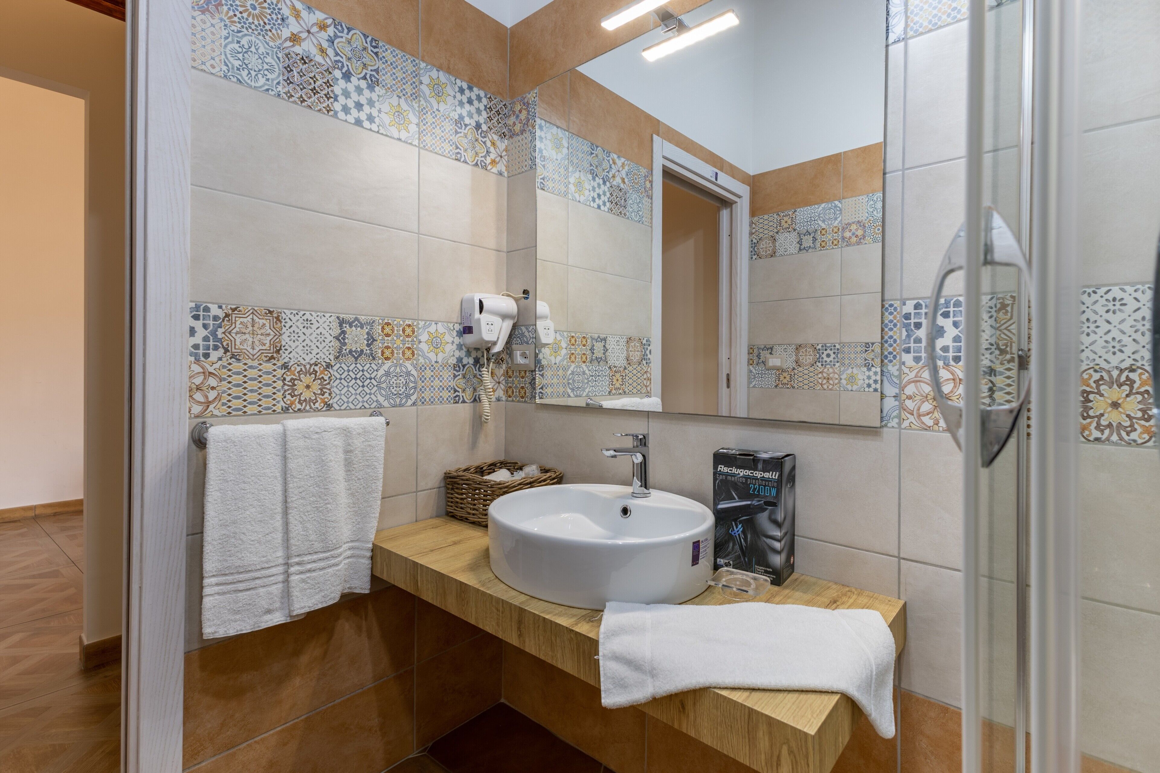 A bathroom with a white sink, a mirror, a towel rack, and a shower area.