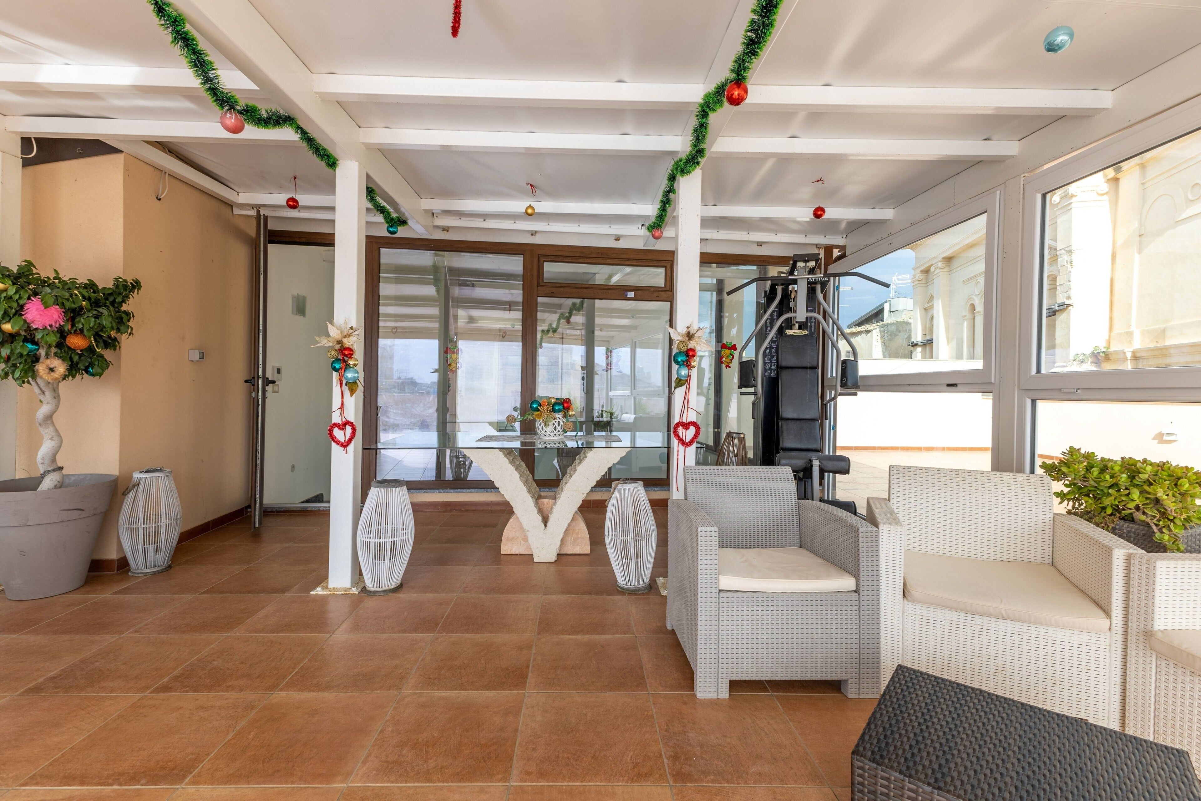 A spacious indoor area with a seating area, a glass table, and a view of the outside.