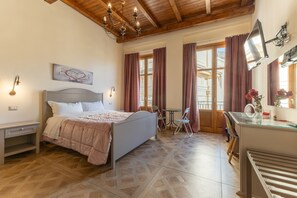 A bedroom with a bed, bedside tables, a desk, a chair, a TV, and a window with curtains. - Room 'Al Duomo - Camera Queen' with Shared Terrace, Wi-Fi and Air Conditioning (Licata)