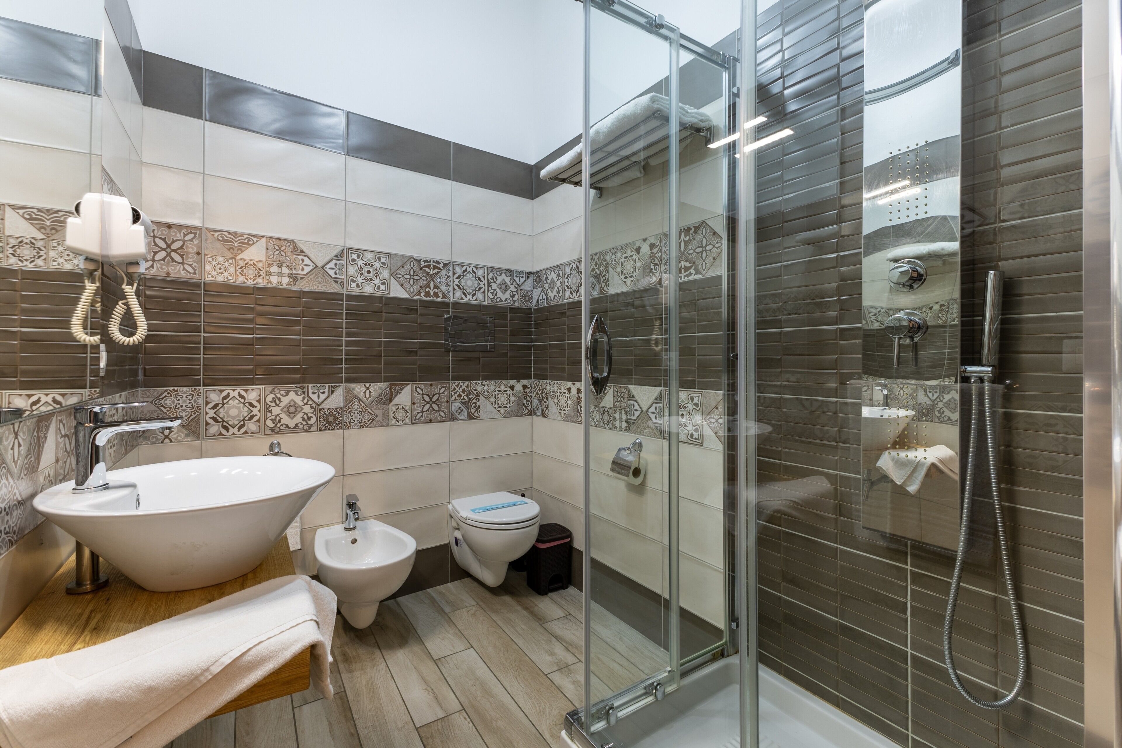 Ein modernes Badezimmer mit einer gläsernen Duschkabine, einem freistehenden Waschbecken, einem Bidet und einer Toilette.