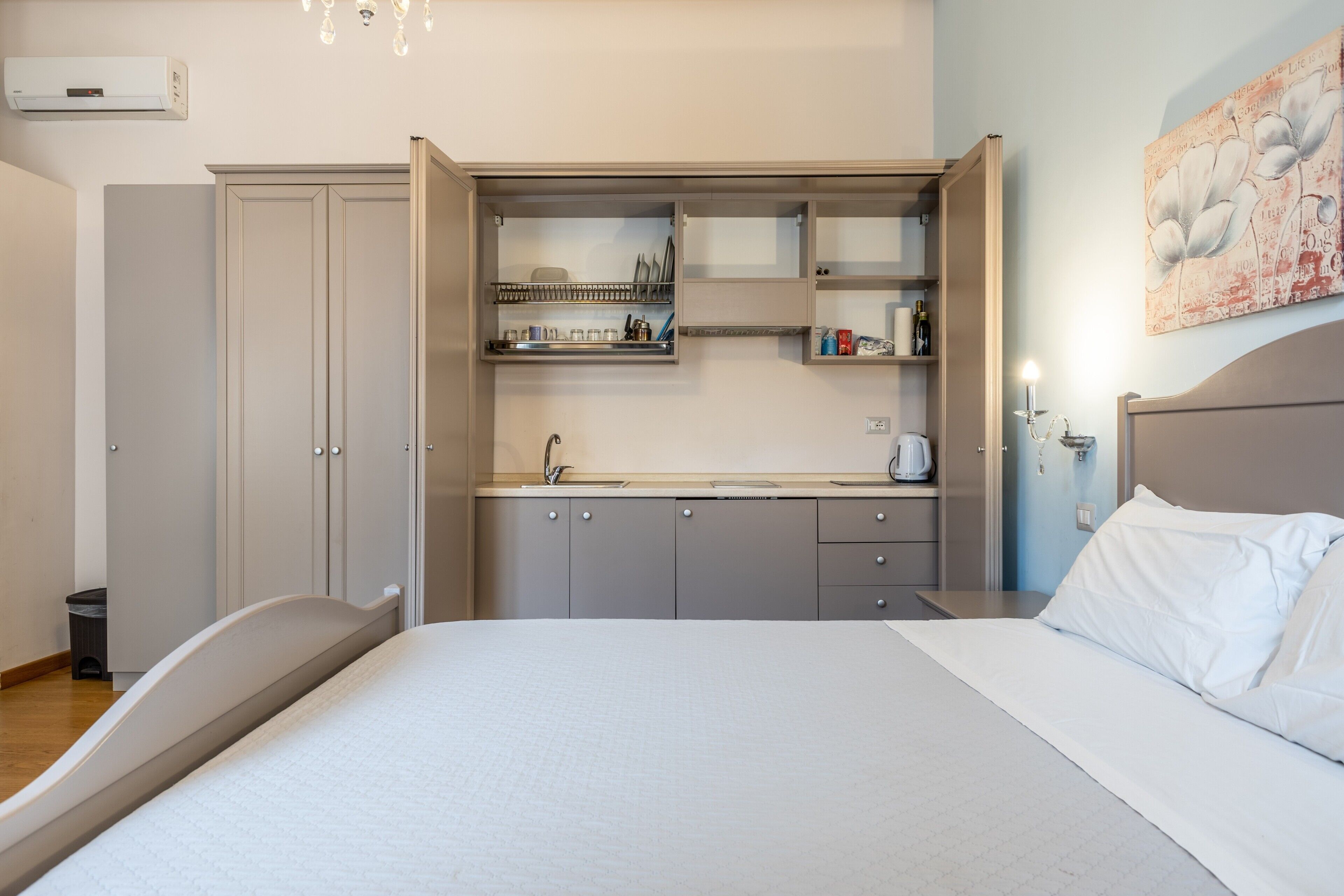 A bedroom with a bed, a built-in wardrobe, a bedside table, and a wall-mounted shelf with toiletries.