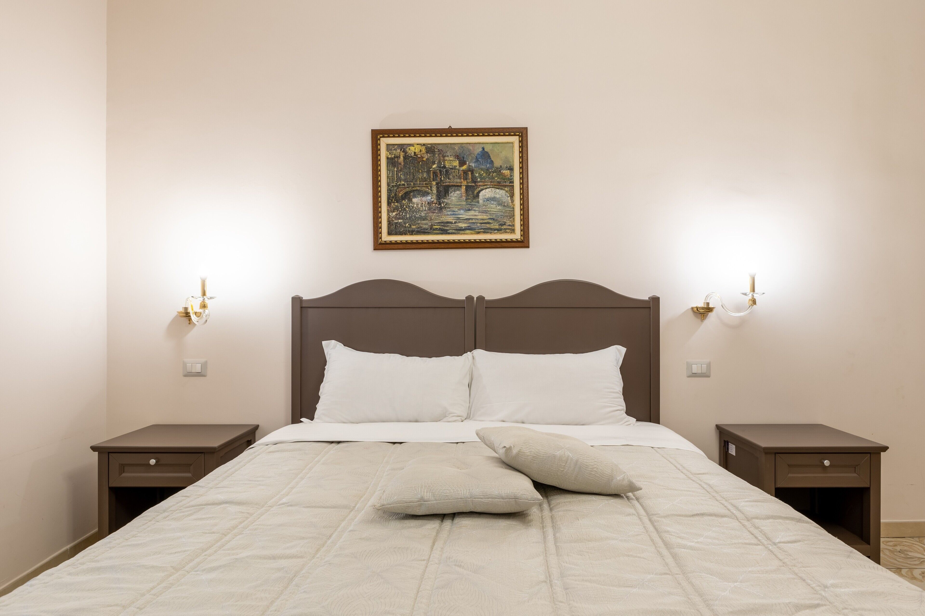 A neatly made bed with white linens, two bedside tables, and a painting on the wall.