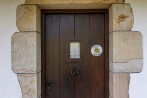 Una puerta de madera con un panel de vidrio, un llamador de metal y un marco de piedra.