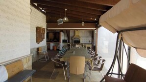 A long dining table with chairs, a kitchen area, and a tent-like structure.