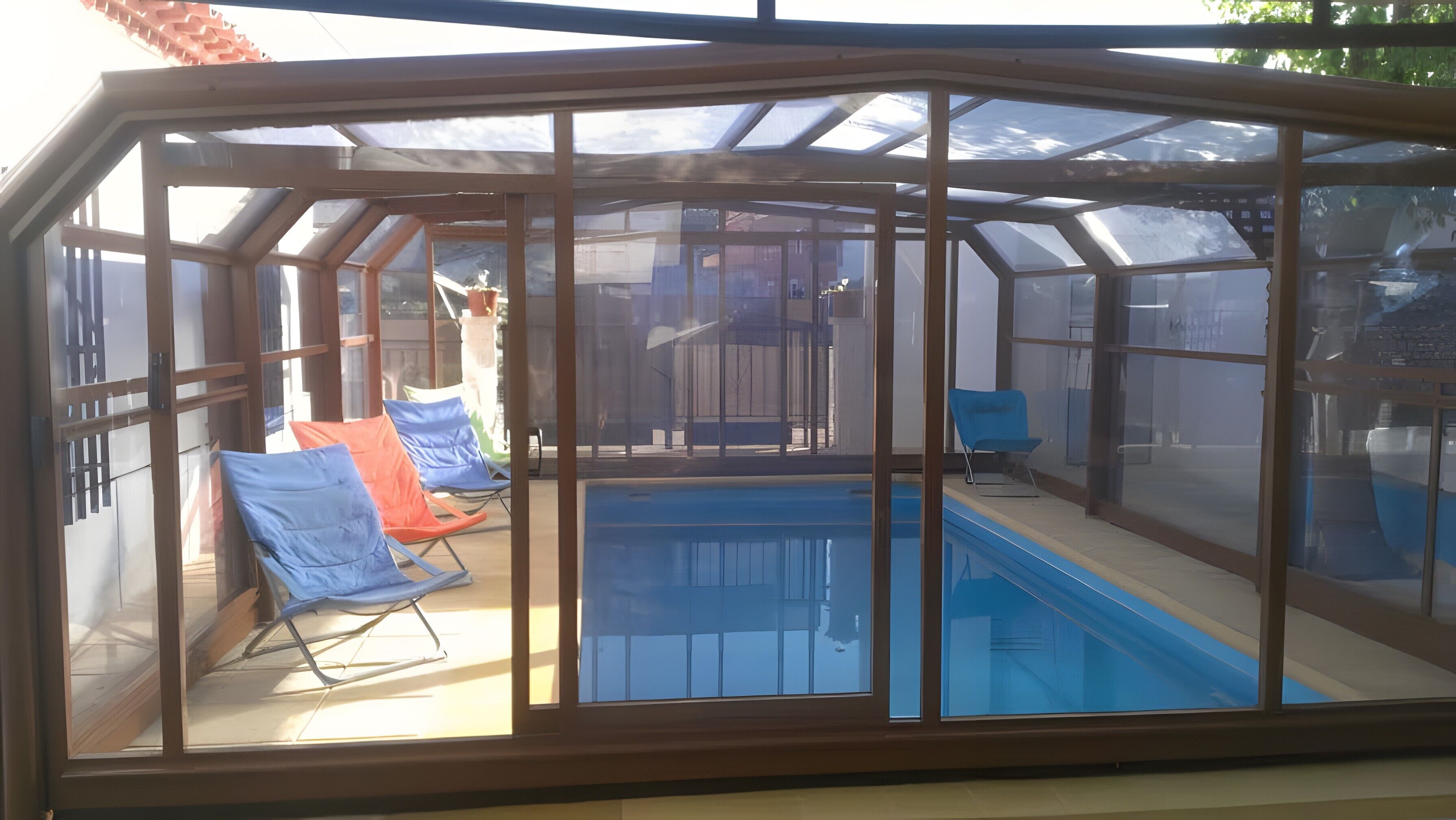A sunroom with a pool, chairs, and a blue chair.
