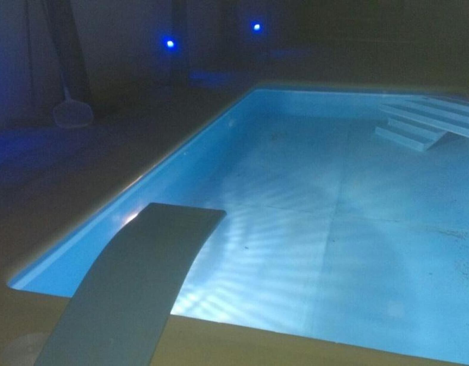 A swimming pool with a dark interior and a blue light.