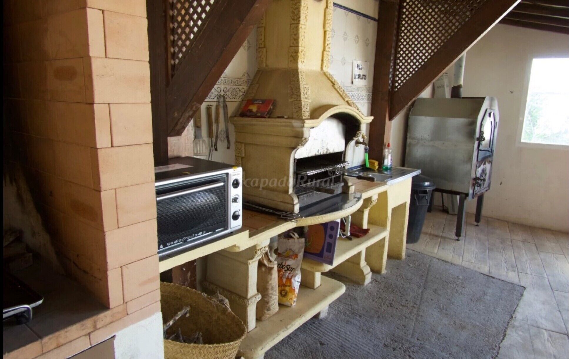 A rustic kitchen with a wood-fired oven, a toaster, and a sink.